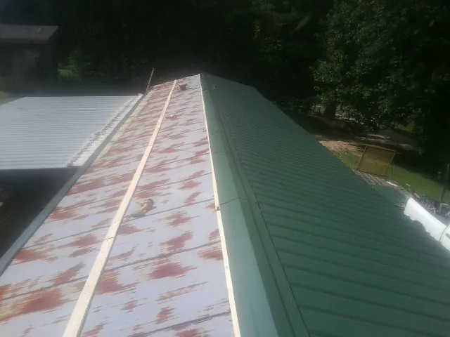 Old rusted panels beside newly installed green metal roofing — Wind Damage Roof Repair by Roofing Brothers in Doylestown