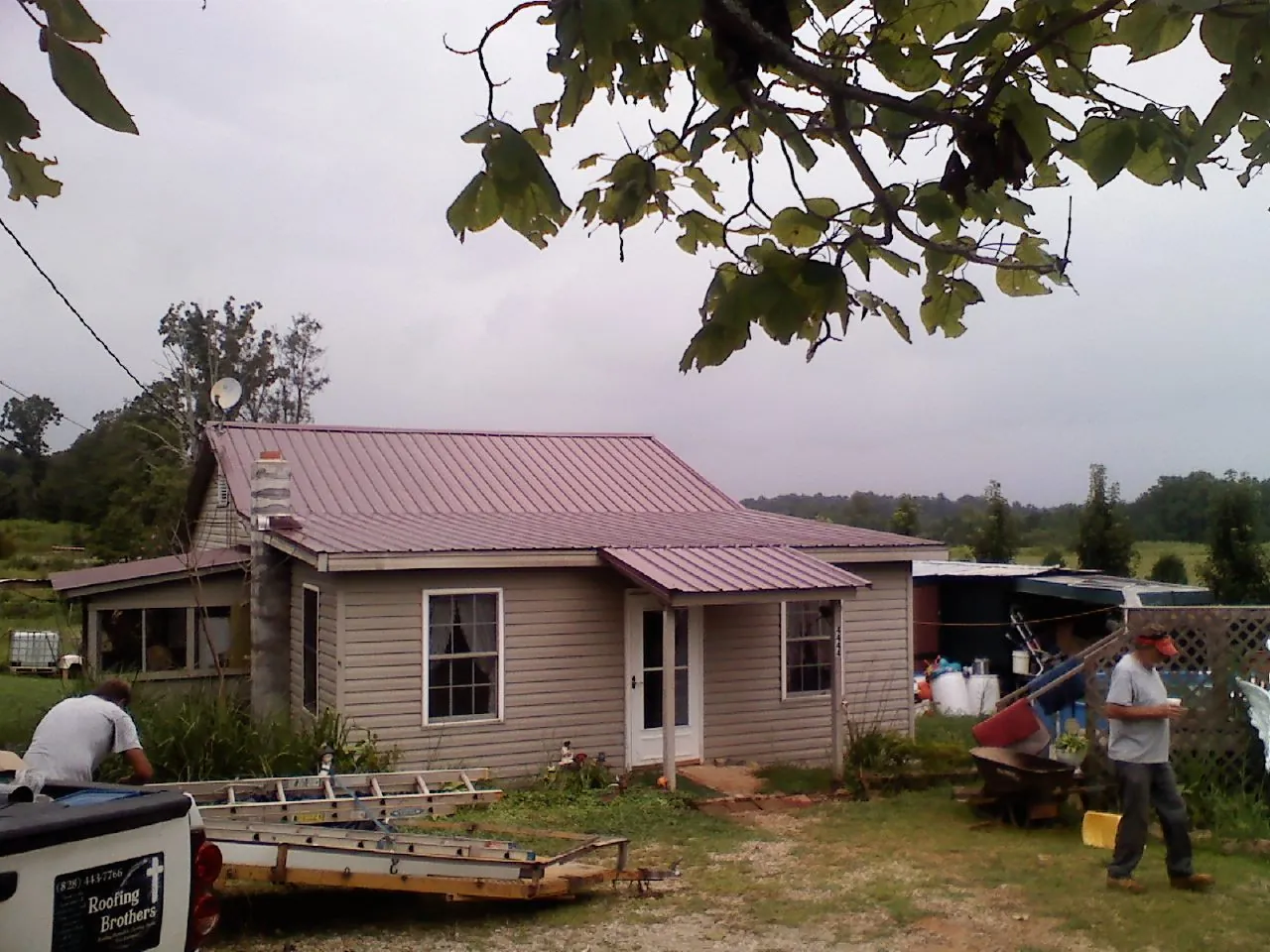 Crew finishing a mauve metal roof on a small farmhouse in Doylestown