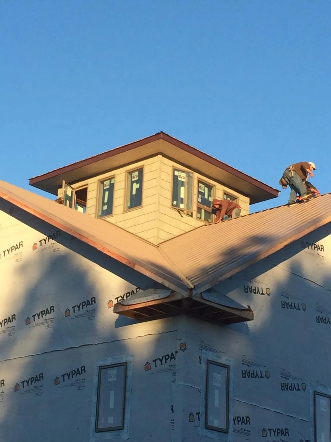 Roofers working around a rooftop cupola on a new metal roof at sunset — Roof Waterproofing in Doylestown by Roofing Brothers